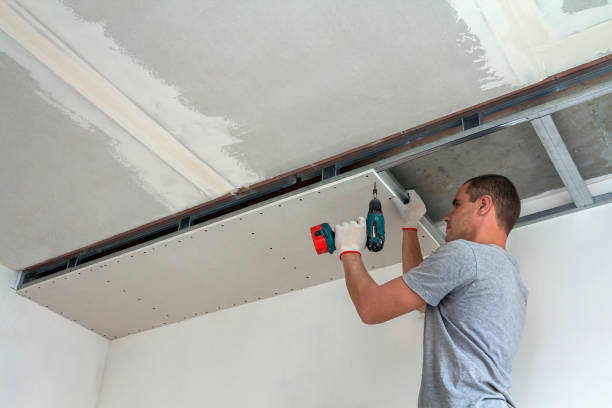 Worker cutting gypsum board for a new ceiling