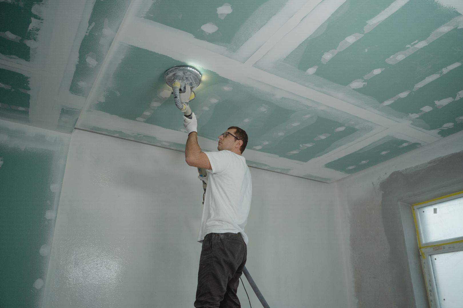 Worker smoothing and finishing a ceiling surface
